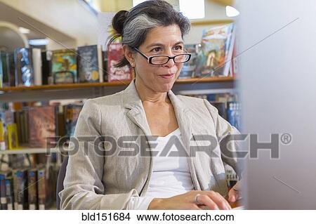 Older Hispanic woman using computer in library View Large Photo Image Picture - Older Hispanic woman using computer in library. Fotosearch