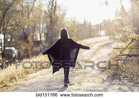 Stock Photograph - Older Hispanic woman walking on dirt path. Fotosearch