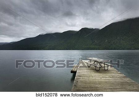 Stock Photo - Picnic table on wooden pier at still remote lake. Fotosearch