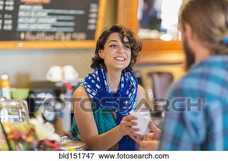 Stock Photo - Server giving cup of coffee to customer in cafe. Fotosearch