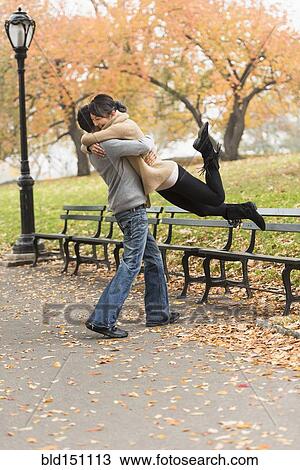 Stock Image - Smiling couple hugging in park. Fotosearch