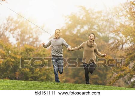Smiling couple running in park View Large Photo Image Stock Image - Smiling couple running in park. Fotosearch