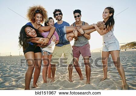 Stock Photo - Smiling friends posing together on beach. Fotosearch