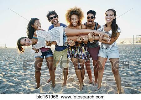 Stock Photograph - Smiling friends posing together on beach. Fotosearch