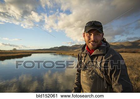 Stock Image - Smiling man standing near river. Fotosearch