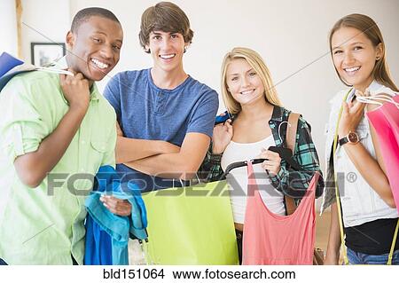 Picture - Smiling teenagers holding shopping bags. Fotosearch