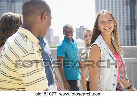 Stock Photo - Smiling teenagers walking on urban rooftop. Fotosearch