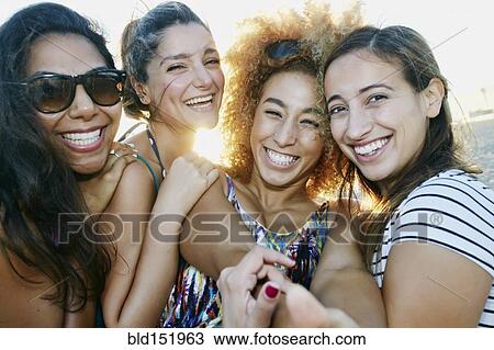 Stock Image - Smiling women taking selfie together outdoors. Fotosearch
