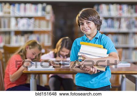 Student carrying stack of books in library View Large Photo Image Stock Photo - Student carrying stack of books in library. Fotosearch