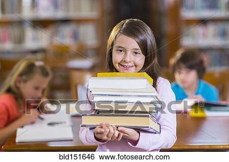 Stock Photograph - Student carrying stack of books in library. Fotosearch