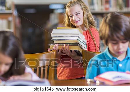 Student carrying stack of books in library View Large Photo Image Stock Photography - Student carrying stack of books in library. Fotosearch