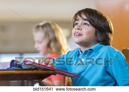 Stock Image - Student reading book at desk. Fotosearch
