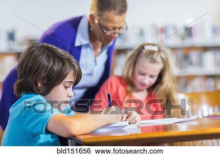 Stock Photograph - Student writing in notebook in library. Fotosearch