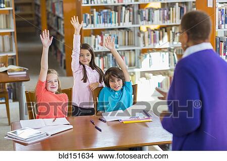 Students raising their hands in library View Large Photo Image Picture - Students raising their hands in library. Fotosearch