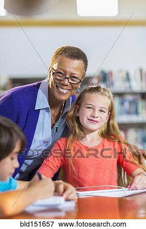 Stock Photo - Teacher and student smiling in library. Fotosearch