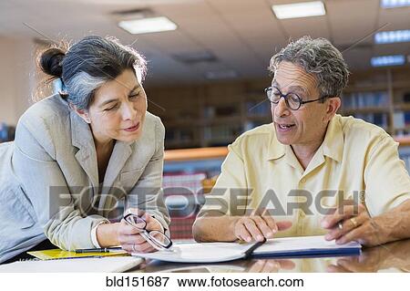 Teacher helping adult student in library View Large Photo Image Stock Photo - Teacher helping adult student in library. Fotosearch