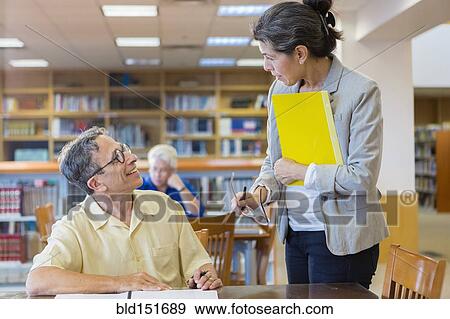 Teacher helping adult student in library View Large Photo Image Stock Photo - Teacher helping adult student in library. Fotosearch