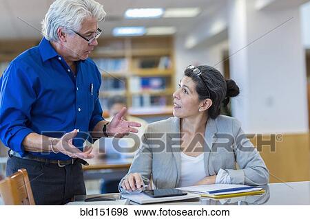 Teacher helping adult student in library View Large Photo Image Stock Photo - Teacher helping adult student in library. Fotosearch