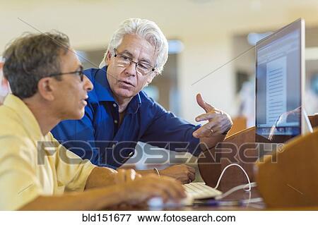 Teacher helping adult student use computer in library View Large Photo Image Stock Photo - Teacher helping adult student use computer in library. Fotosearch