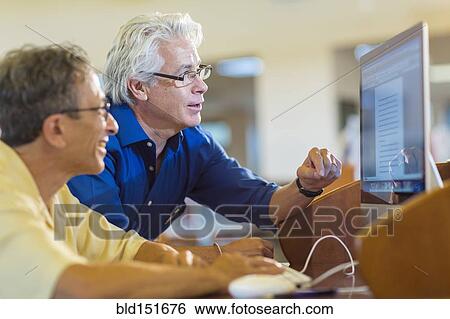 Teacher helping adult student use computer in library View Large Photo Image Stock Photograph - Teacher helping adult student use computer in library. Fotosearch