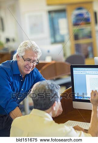 Teacher helping adult student use computer in library View Large Photo Image Stock Photography - Teacher helping adult student use computer in library. Fotosearch