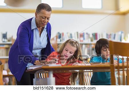 Teacher helping student in classroom View Large Photo Image Stock Photo - Teacher helping student in classroom. Fotosearch