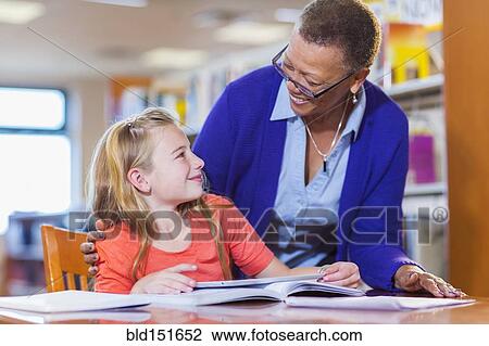 Teacher helping student in library View Large Photo Image Stock Image - Teacher helping student in library. Fotosearch