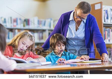 Stock Photo - Teacher helping student in library. Fotosearch