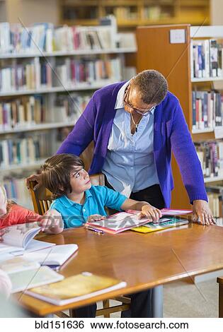 Teacher helping student in library View Large Photo Image Stock Photograph - Teacher helping student in library. Fotosearch