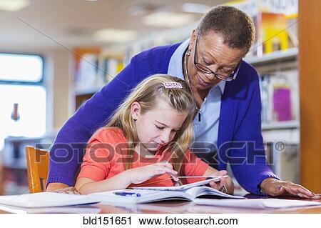 Teacher helping student use digital tablet in library View Large Photo Image Stock Image - Teacher helping student use digital tablet in library. Fotosearch