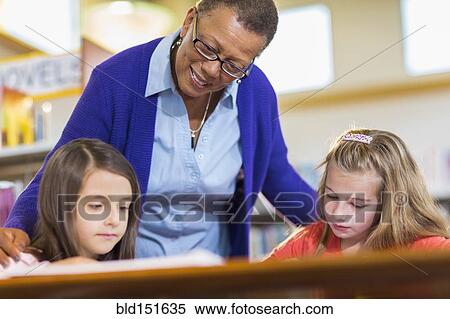 Teacher helping students in library View Large Photo Image Stock Photography - Teacher helping students in library. Fotosearch