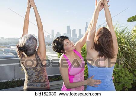 Teacher helping yoga students in class on urban rooftop View Large Photo Image Stock Image - Teacher helping yoga students in class on urban rooftop. Fotosearch