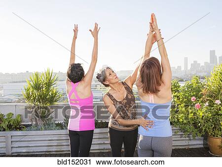 Teacher helping yoga students in class on urban rooftop View Large Photo Image Stock Image - Teacher helping yoga students in class on urban rooftop. Fotosearch