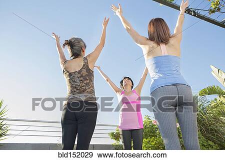 Stock Photo - Teacher working with yoga students in class outdoors. Fotosearch