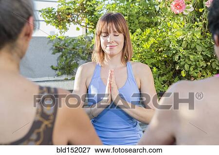 Stock Photo - Teacher working with yoga students outdoors. Fotosearch