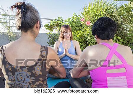 Stock Photograph - Teacher working with yoga students outdoors. Fotosearch