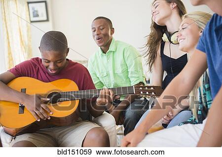 Teenage boy playing guitar at party View Large Photo Image Stock Photo - Teenage boy playing guitar at party. Fotosearch