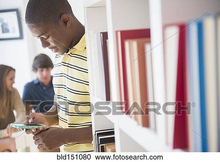 Stock Image - Teenage boy using cell phone at party. Fotosearch