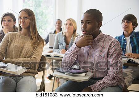 Stock Image - Teenage students listening in classroom. Fotosearch