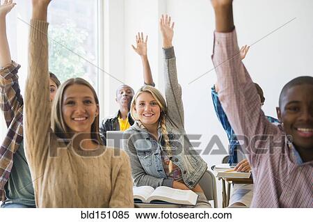 Stock Photography - Teenage students raising hands in classroom. Fotosearch