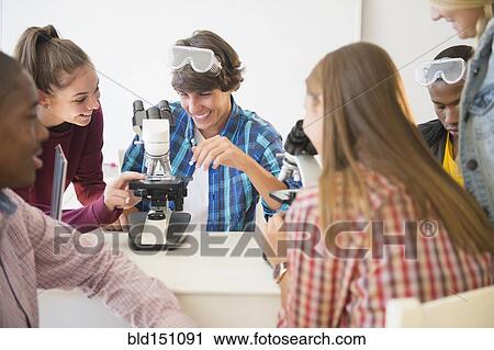 Stock Image - Teenage students using microscope in science laboratory. Fotosearch