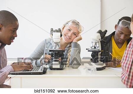 Stock Image - Teenage students using microscopes in science laboratory. Fotosearch