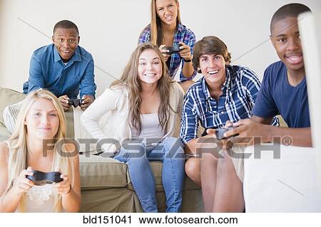 Stock Image - Teenagers playing video games in living room. Fotosearch