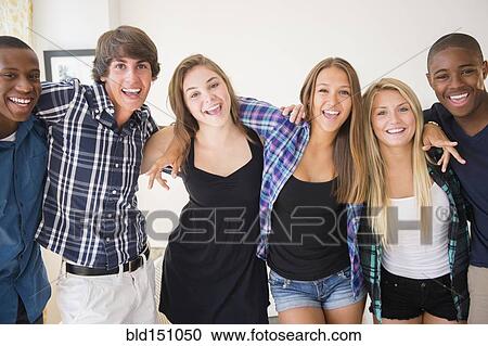 Stock Image - Teenagers smiling in living room. Fotosearch