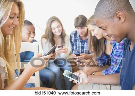 Stock Image - Teenagers using cell phones. Fotosearch