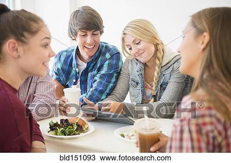 Stock Image - Teenagers using digital tablet at table. Fotosearch