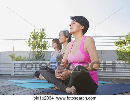 Picture - Women meditating together on rooftop. Fotosearch