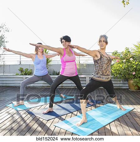 Picture - Women practicing yoga together on urban rooftop. Fotosearch