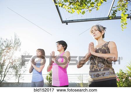 Stock Photo - Women practicing yoga together on urban rooftop. Fotosearch