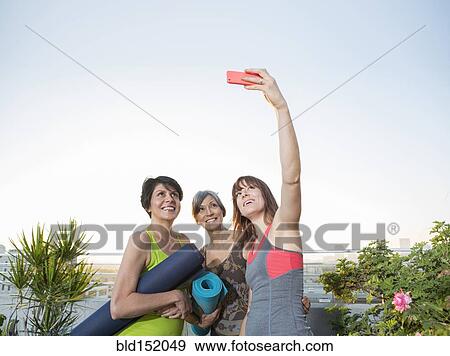 Women taking cell phone selfie on urban rooftop View Large Photo Image Stock Photo - Women taking cell phone selfie on urban rooftop. Fotosearch
